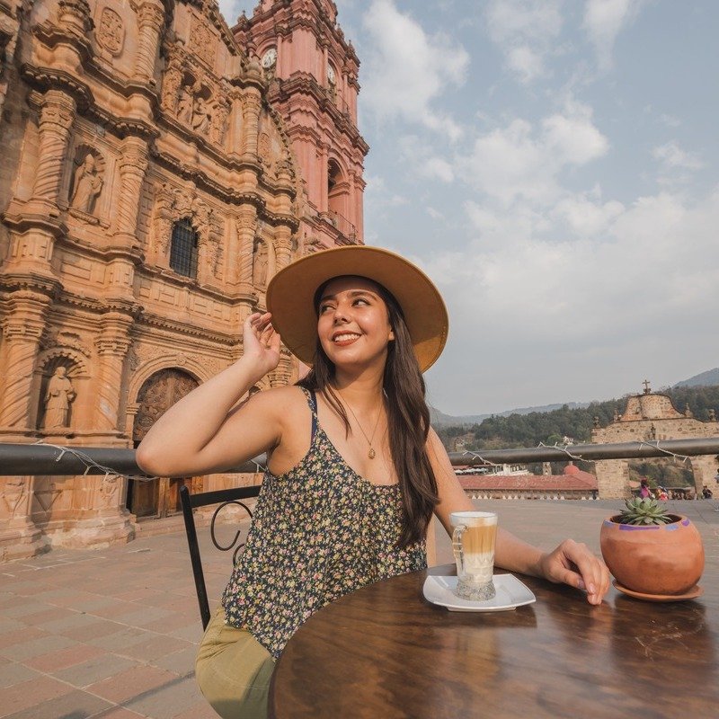 Young Smiling Happy Traveler Having A Coffee Facing A Historical Basilica In Mexico