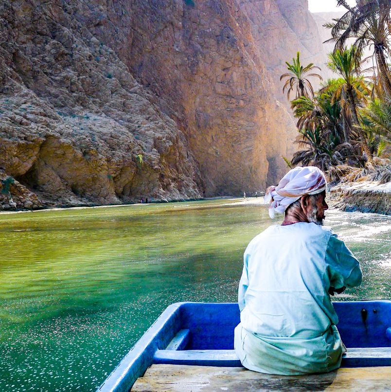 Wadi Shab Oman, man in boat in lake at bottom of canyone