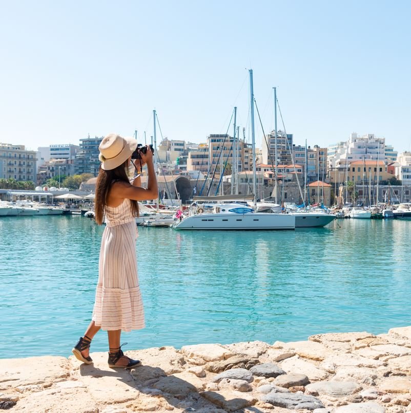 Woman taking a picture of boats in Crete, Greece, destinations