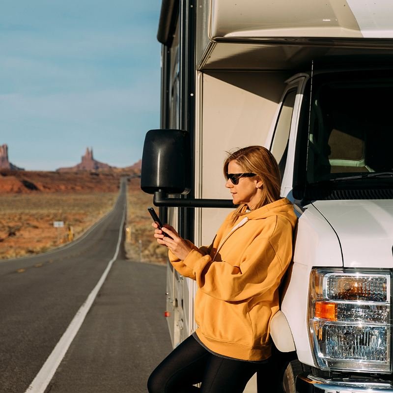 Woman using phone next to RV in the road