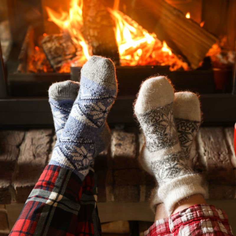 Couple in pajamas resting near fireplace indoors, closeup. Winter vacation