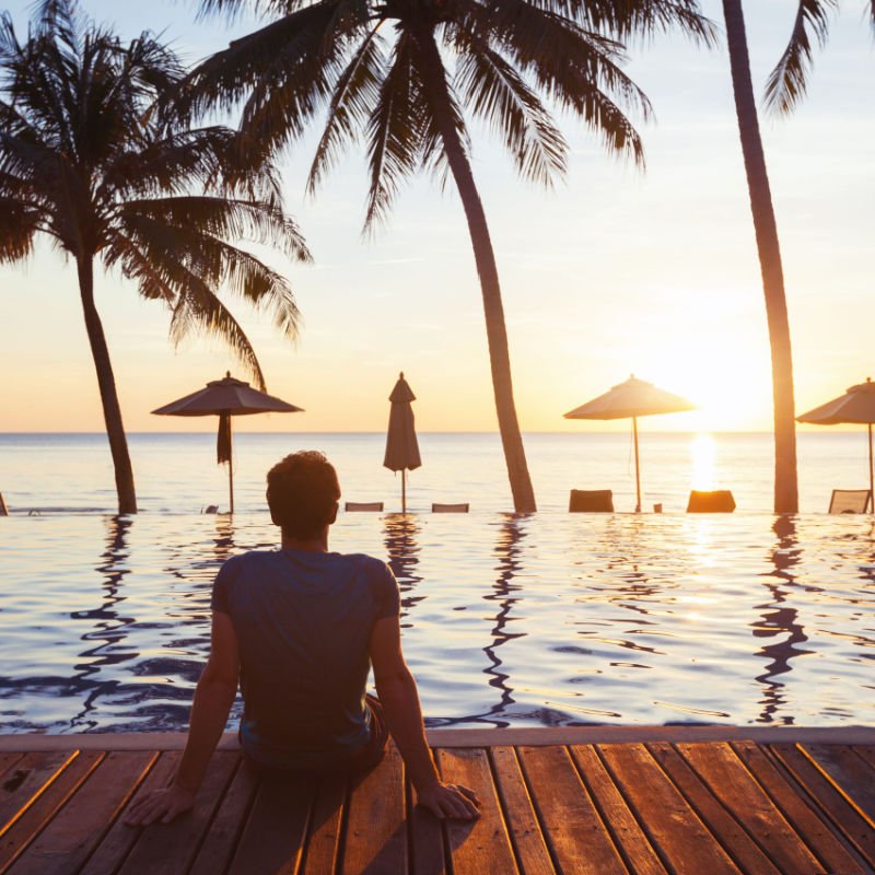 relaxation on the beach, young man enjoying beautiful sunset in luxury hotel near swimming pool