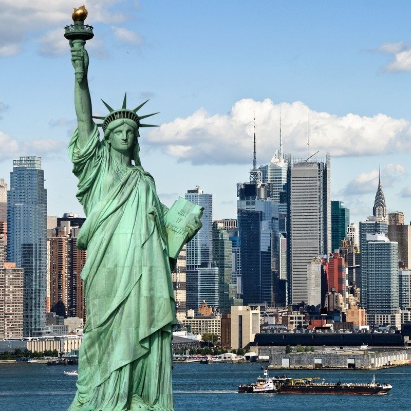 The Statue Of Liberty Pictured Against The Backdrop Of The Manhattan Skyline In New York City, United States