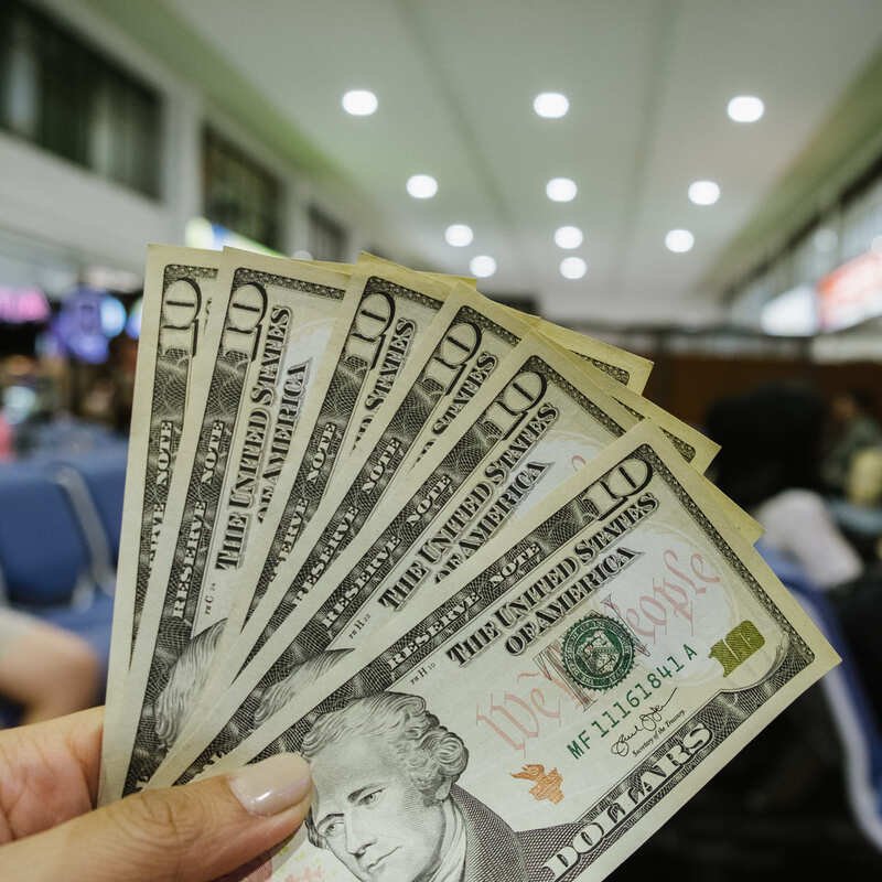 Traveler Holding Up US Dollars At The Airport, International Travel