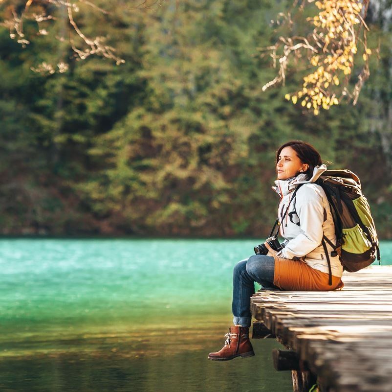 Woman sitting on a dock over a pond looking out over the water