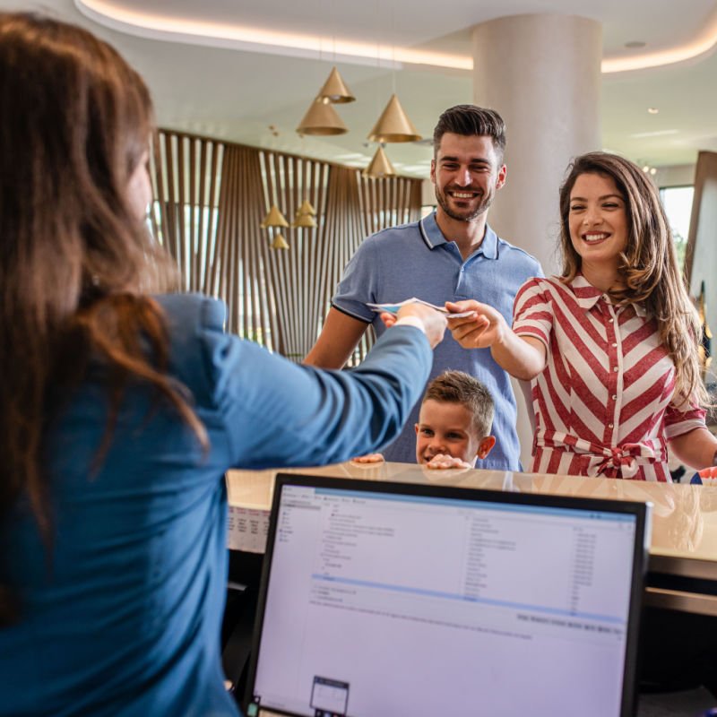 A family of three checks in at a hotel with a day pass