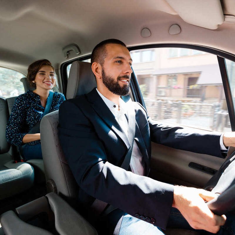 Smiling-Taxi-Uber-Driver-Taking-Female-Passenger-To-Her-Destination