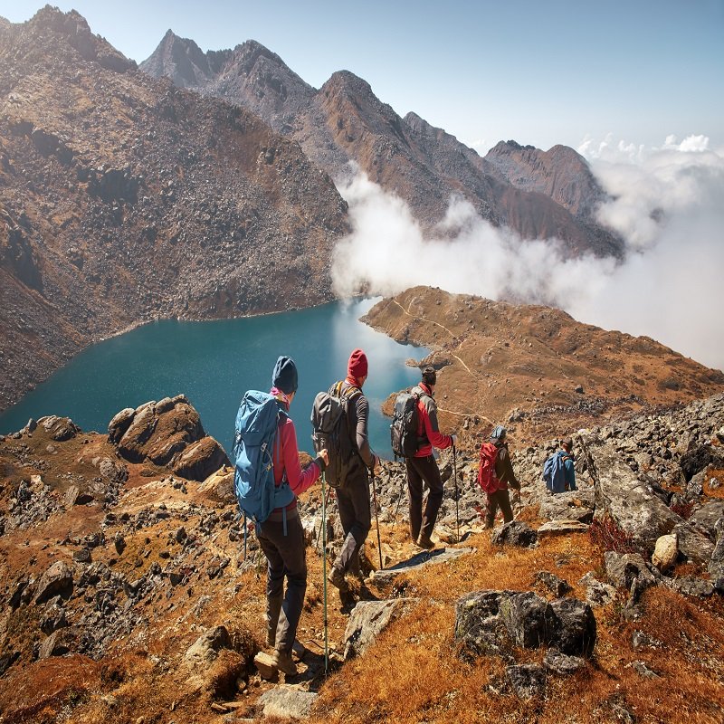 Group tourists with Backpacks descends down on Mountain Trail during Hike.