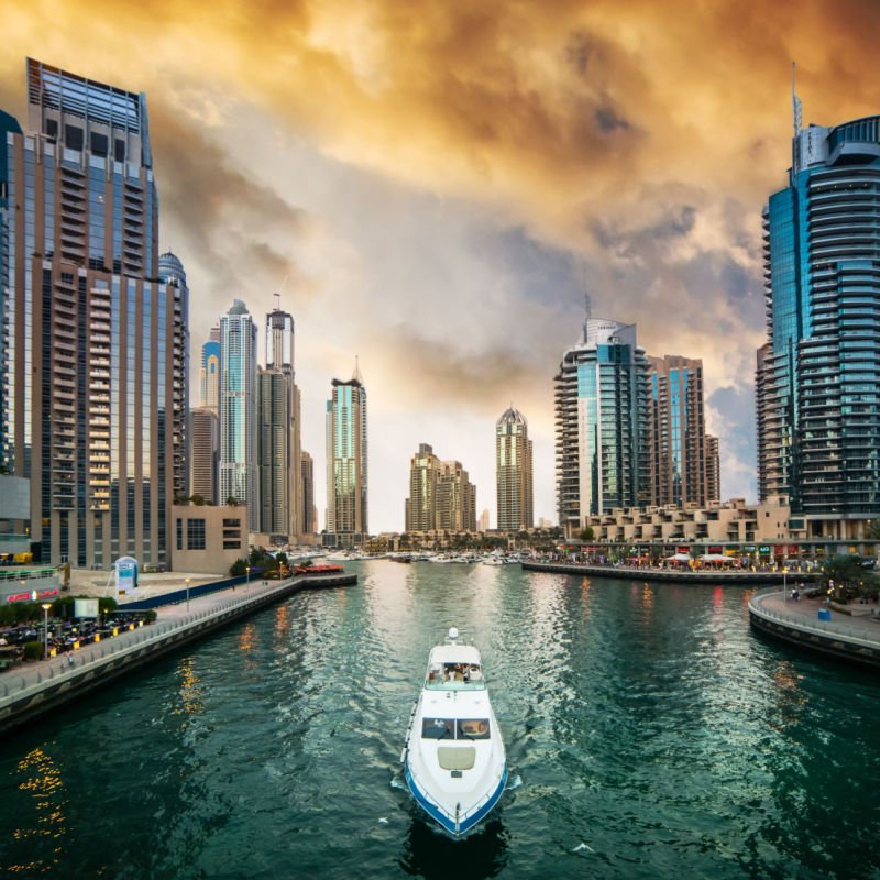 Modern skyscrapers and water channel with boats of Dubai Marina at sunset, United Arab Emirates