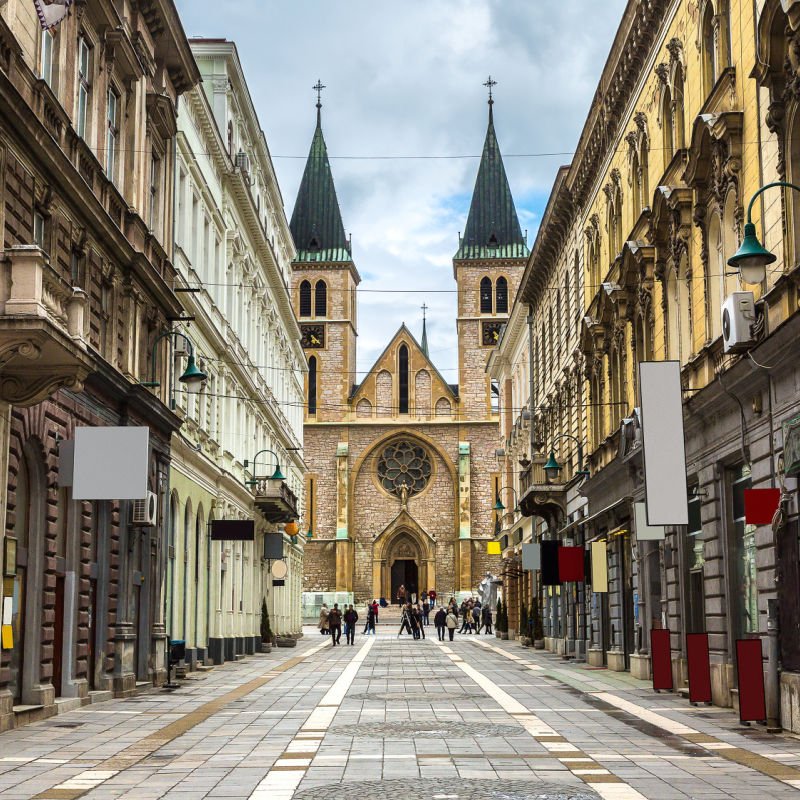 sarajevo street with people walking across it and a church in the background