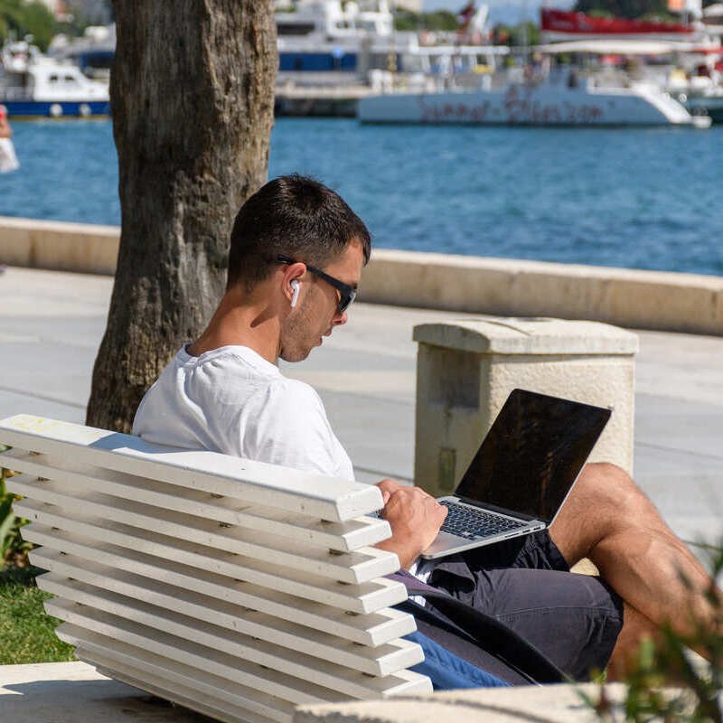 Young Man Working From His Computer At The Seafront Promenade, Split, Croatia