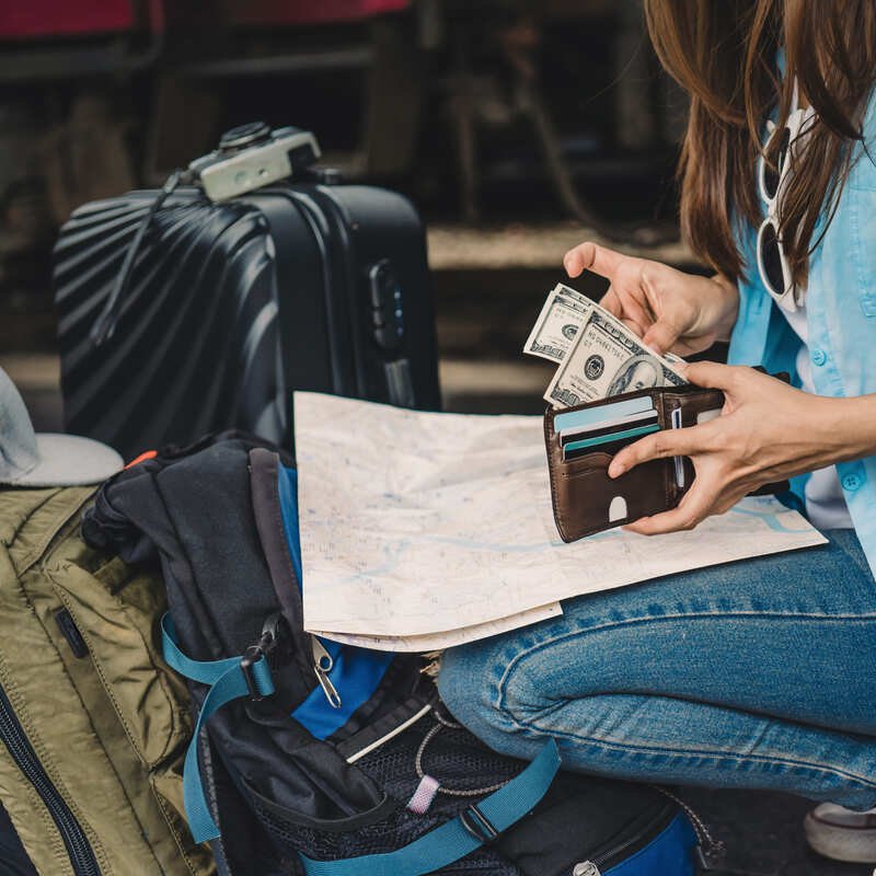 Female Traveler Counting Cash As She Packs Her Bags Ahead Of Traveling