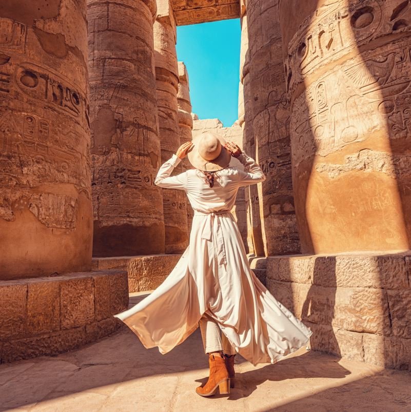 Woman looking up at some columns in egypt