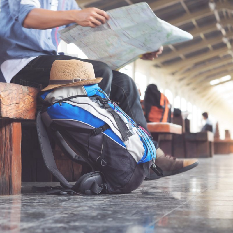 Backpack and hat at the train station with a traveler.