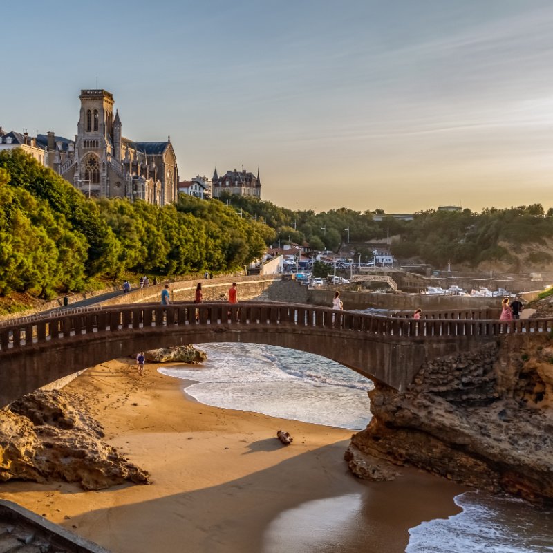 View of the famous stone bridge to the Rocher du Basta, cityscape and coastline with sand beaches and port for small boats. Golden hour. Holidays in France.