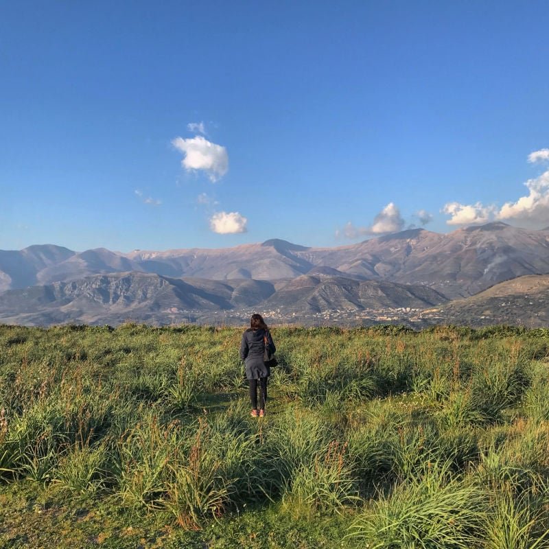 woman in field in albania with mountains 