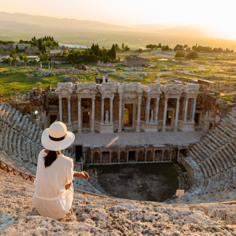 Hierapolis ancient city Pamukkale Turkey, young woman with hat watching sunset by the ruins Unesco copy