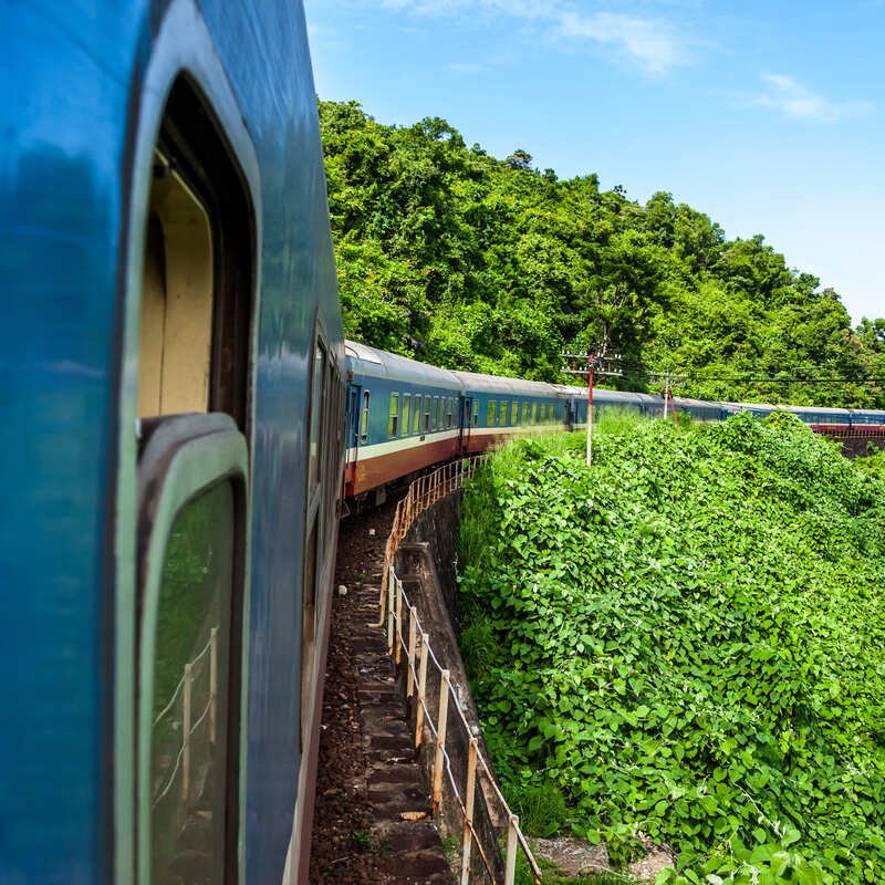 View Of A Train From The Window As It Enters A Curve In A Natural Mountain Setting In Southern Vietnam, Southeast Asia