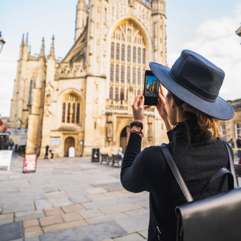 Woman backpack taking picture with smartphone of Bath City UK, United kingdom copy