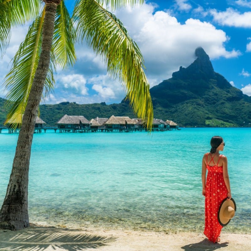 Bora Bora luxury hotel vacation tourist woman relaxing by ocean beach with view of Mt Otemanu in Tahiti, French Polynesia copy