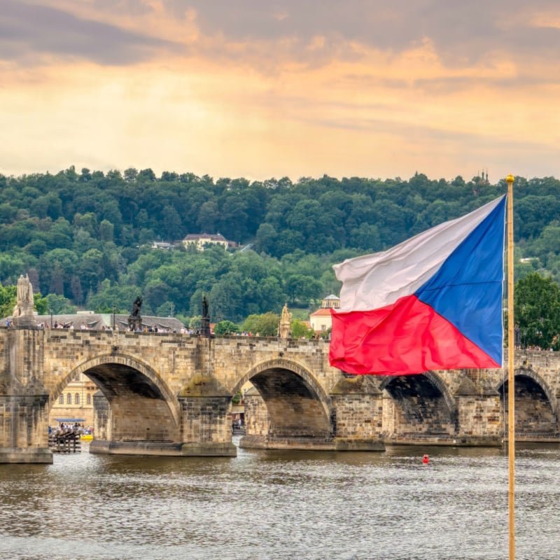 Medieval stone arch bridge over Vltava river in Prague. The national flag of the Czech Republic copy