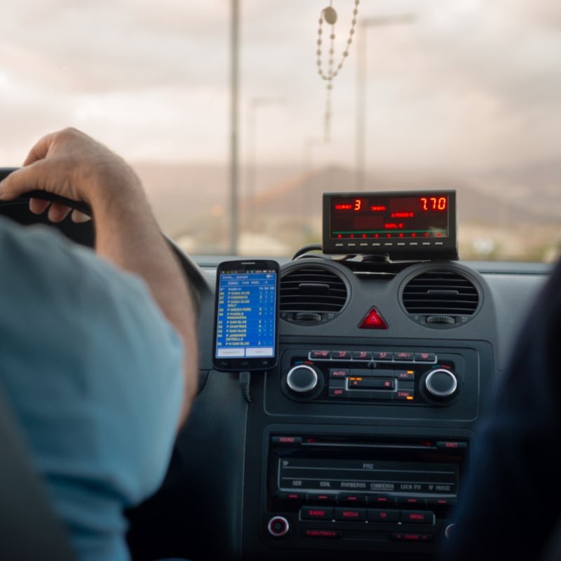 A Taxi Driver Driving A Car With A Taximeter In An Unspecified Location