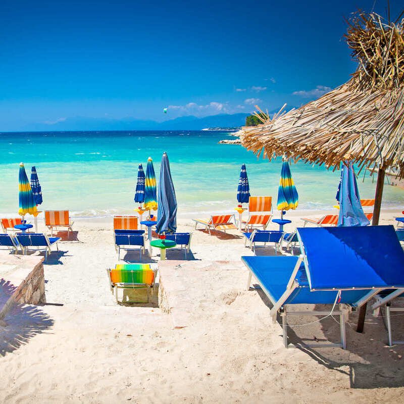 Beach Lounges And Paraols On A Sandy Beach Lapped By The Turquoise Colored Ionian Sea In Ksamil, Albanian Riviera, Albania, Mediterranean Sea, Eastern Europe, Balkan Peninsula