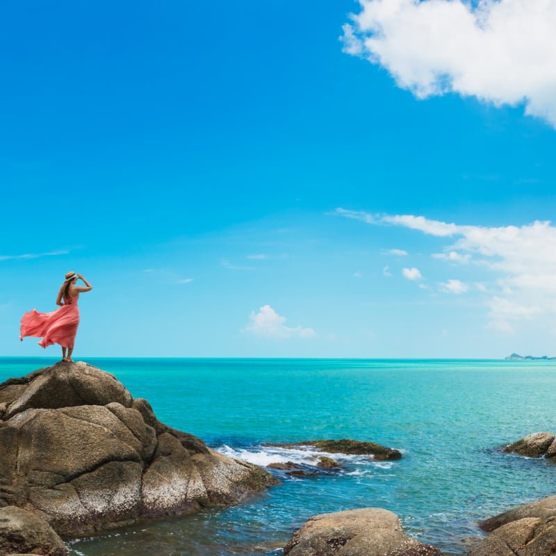 Woman on a rock over ocean in Thailand