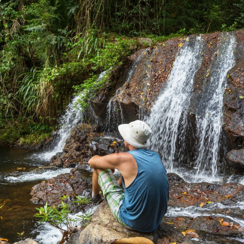 man resting by waterfall in jungle in belize