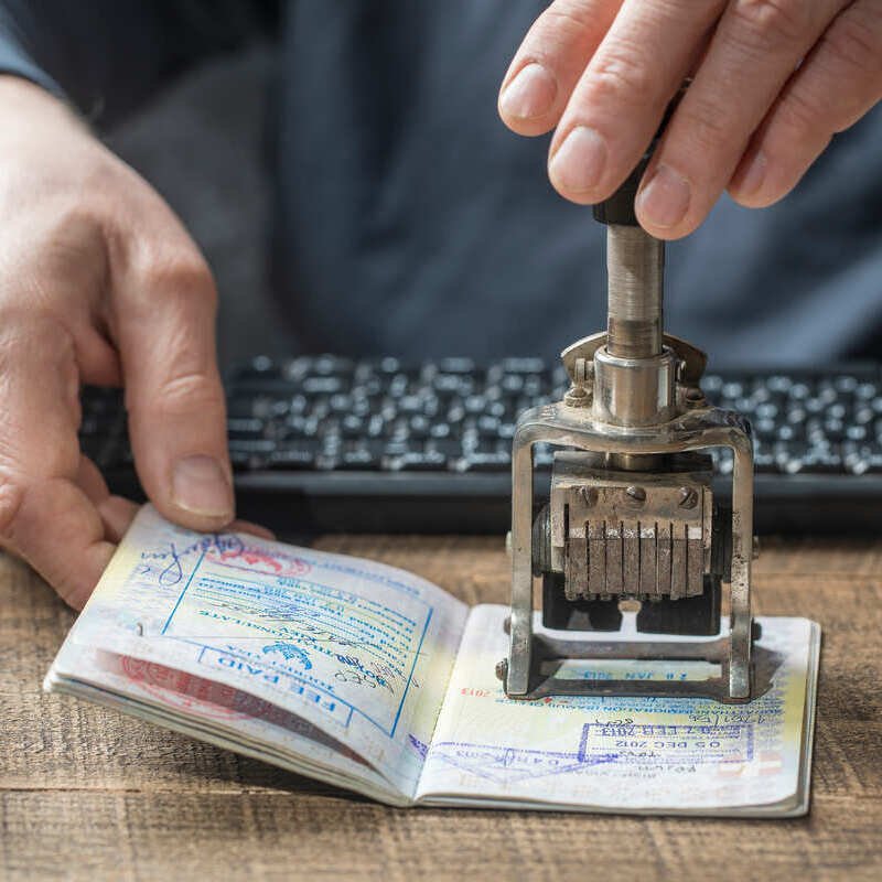 A Border Officer Stamping A Visa Page On An Unspecified Passport, International Travel