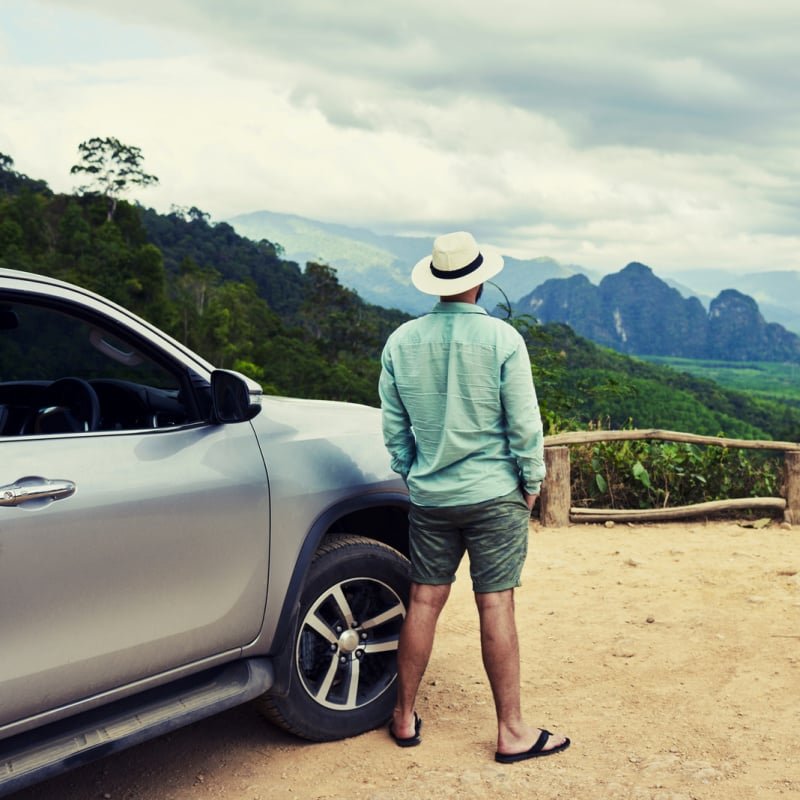 man next to car overlooking mountians