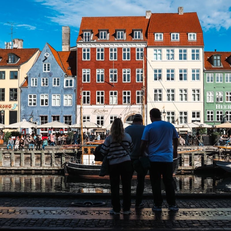 sillouhette of three travelers looking at colorful buildings in nyhavn copenhagen